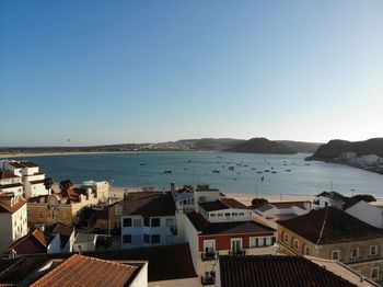 High angle view of townscape by sea against clear sky