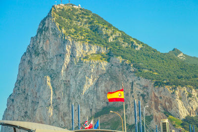 Low angle view of flag on mountain against clear blue sky