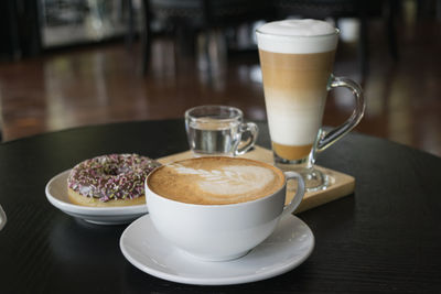 High angle view of coffee and donut served on table