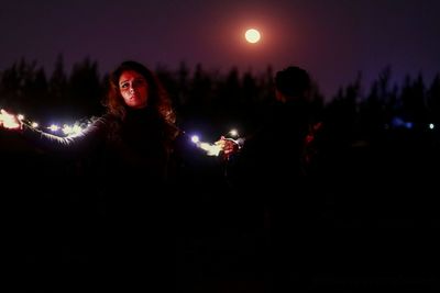 Portrait of young woman standing at night