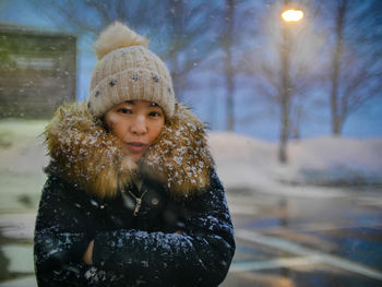 Portrait of woman standing outdoors during snowfall