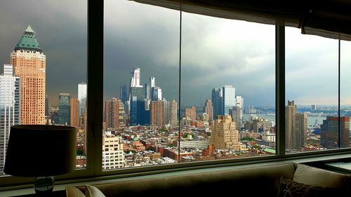 Modern buildings in city against sky seen through glass window
