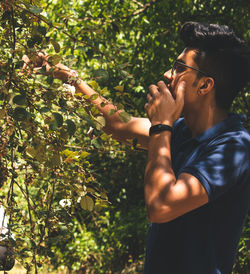 Side view of young man against forest