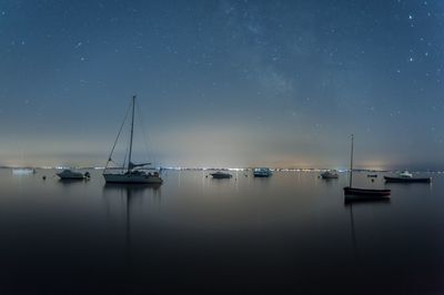 Sailboats sailing in sea against sky at night