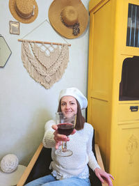 Young woman in beret sits in cozy home, room with music record in hands. vintage yellow cabinet.