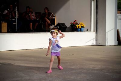 Cute girl dancing on footpath during festival