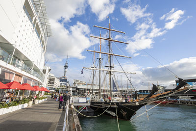 Sailboats moored at harbor against sky