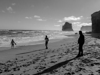 People walking on beach against sky