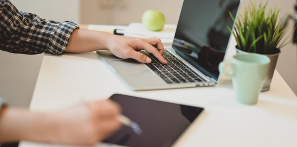 Midsection of man using laptop on table