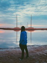 Rear view of man/ woman standing at beach against sky during sunset. scenic view. 