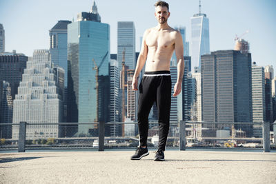 Full length of shirtless man standing on building terrace in city