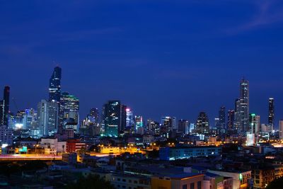 Illuminated cityscape against blue sky