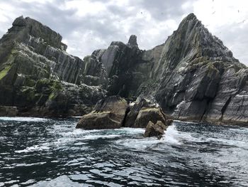 Scenic view of rocky mountains by sea against sky