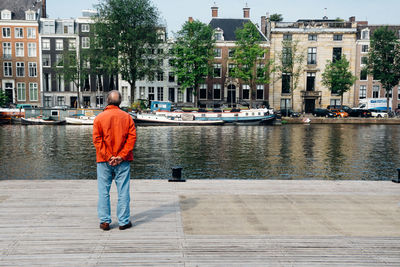 Rear view of man standing on boat in city
