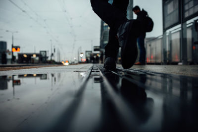 Low section of man walking on road in city