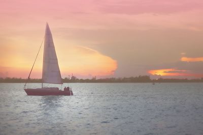 Sailboat sailing on sea against sky during sunset