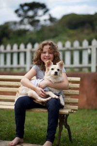 Portrait of happy woman with dog sitting in park