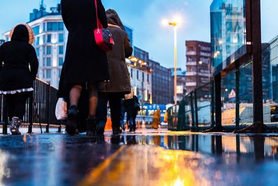 People standing on wet street at night