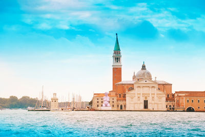 View of buildings by sea against sky in city