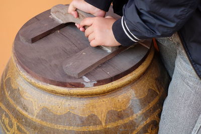 Midsection of woman holding wooden lid on container