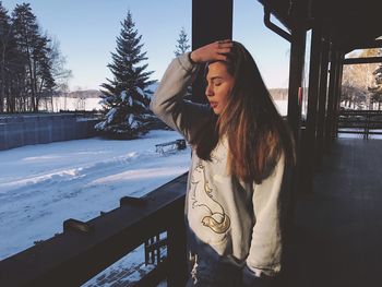 Young woman standing on snow against trees