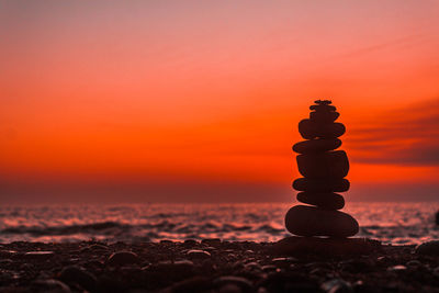 Stack of pebbles on beach during sunset