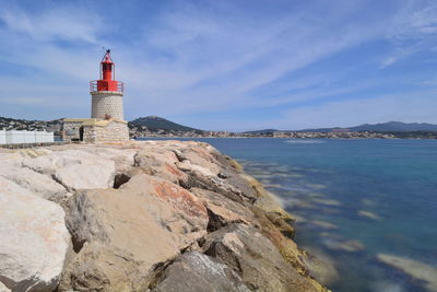 Lighthouse by sea against sky