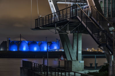 Illuminated bridge over river against sky at night