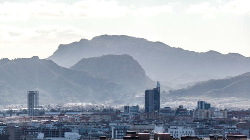 Buildings in city against cloudy sky