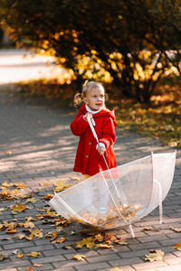 Cute girl holding umbrella while standing outdoors