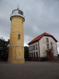 Low angle view of lighthouse by building against sky