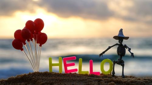 Multi colored balloons on beach against sky during sunset