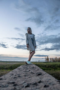 Full length of young woman standing on land against sky