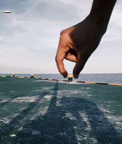 Midsection of person on sea against sky