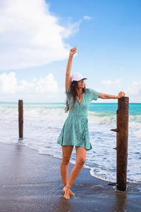 Full length of woman standing on beach against sky