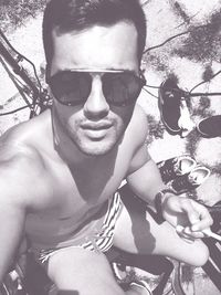 Close-up portrait of young man holding sunglasses