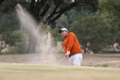 Full length of man climbing on golf course