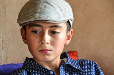 Close-up of boy wearing cap against wall