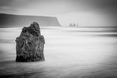 Rock formation in sea against sky