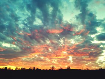 Silhouette landscape against dramatic sky during sunset