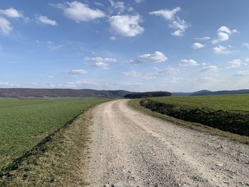 Dirt road amidst field against sky , in eichsfeld, thuringia, germany