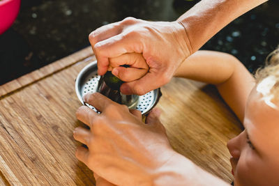 Cropped hands of parent and son squeezing fruit