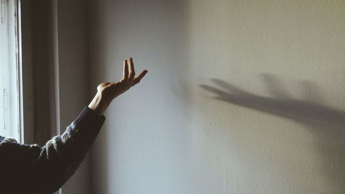 Cropped hand of woman gesturing against wall at home