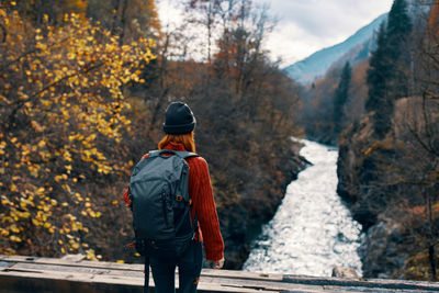 Rear view of man standing by trees during autumn