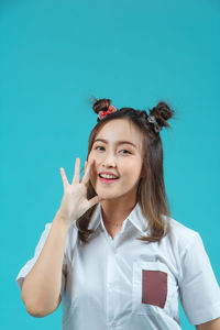 Portrait of smiling young woman standing against clear blue sky