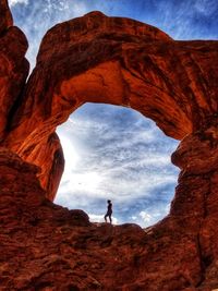 Woman on rock formation against sky