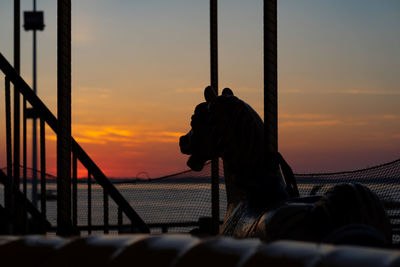 Silhouette person standing by railing against sky during sunset