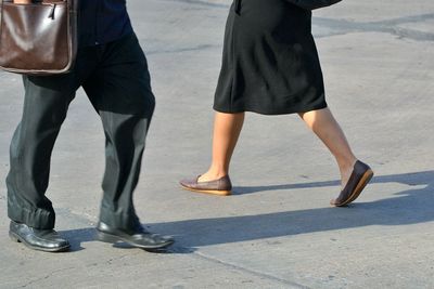 Low section of couple walking on road