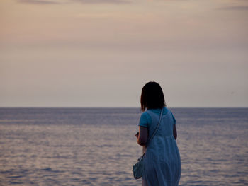 Rear view of man looking at sea against sky