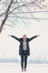 Full length portrait of happy young woman in snow